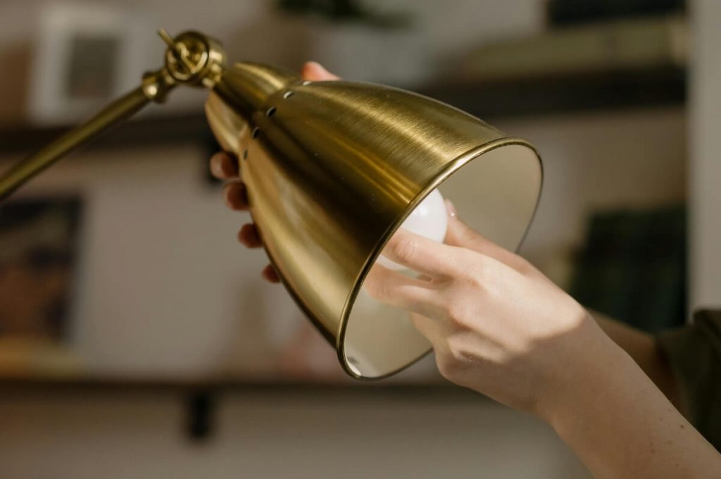 Main qui change une ampoule dans un airbnb, un des services en plus de notre conciergerie.